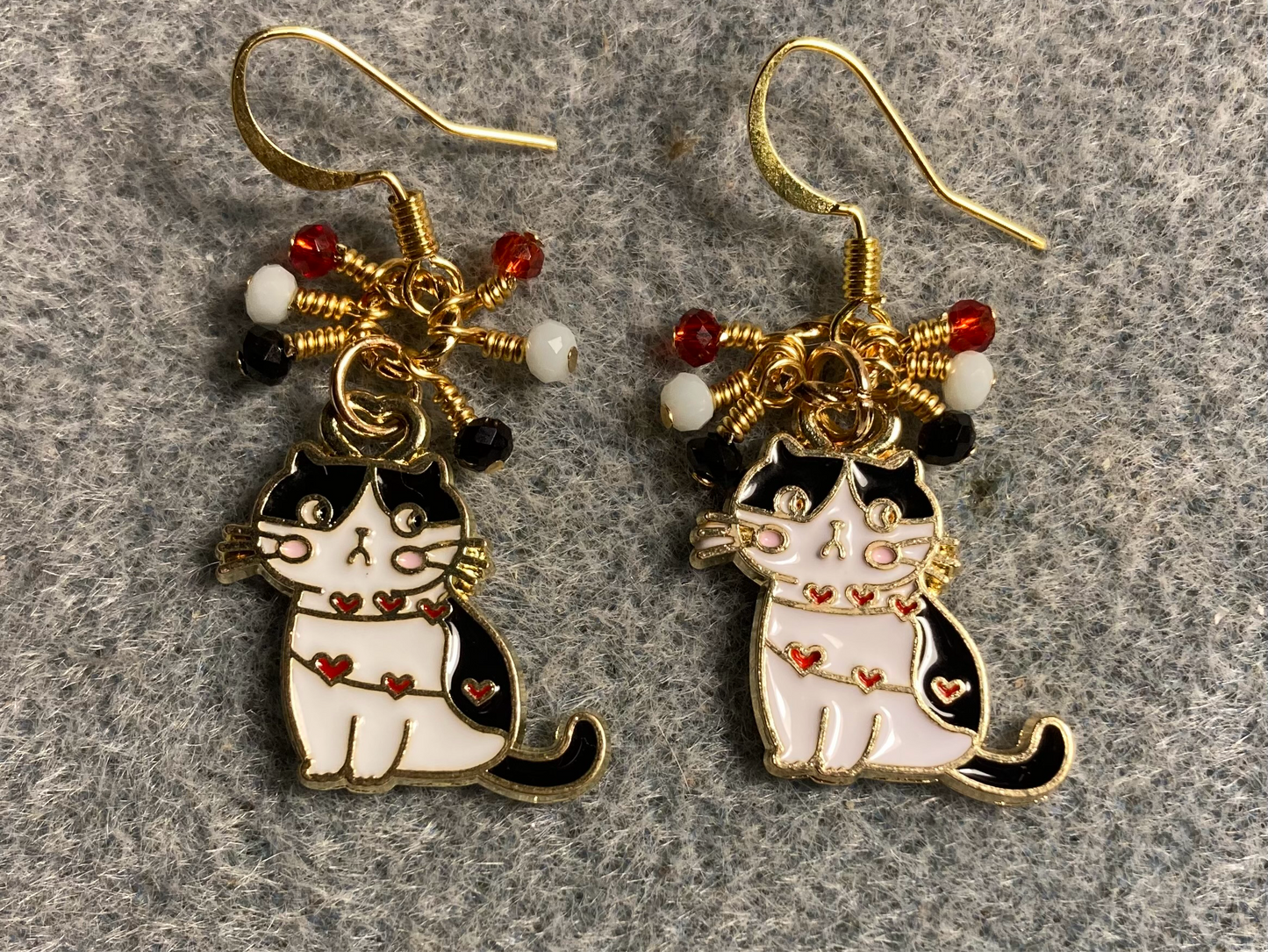 Black, red, and white enamel cat charm earrings adorned with tiny dangling black, red, and white Chinese crystal beads.