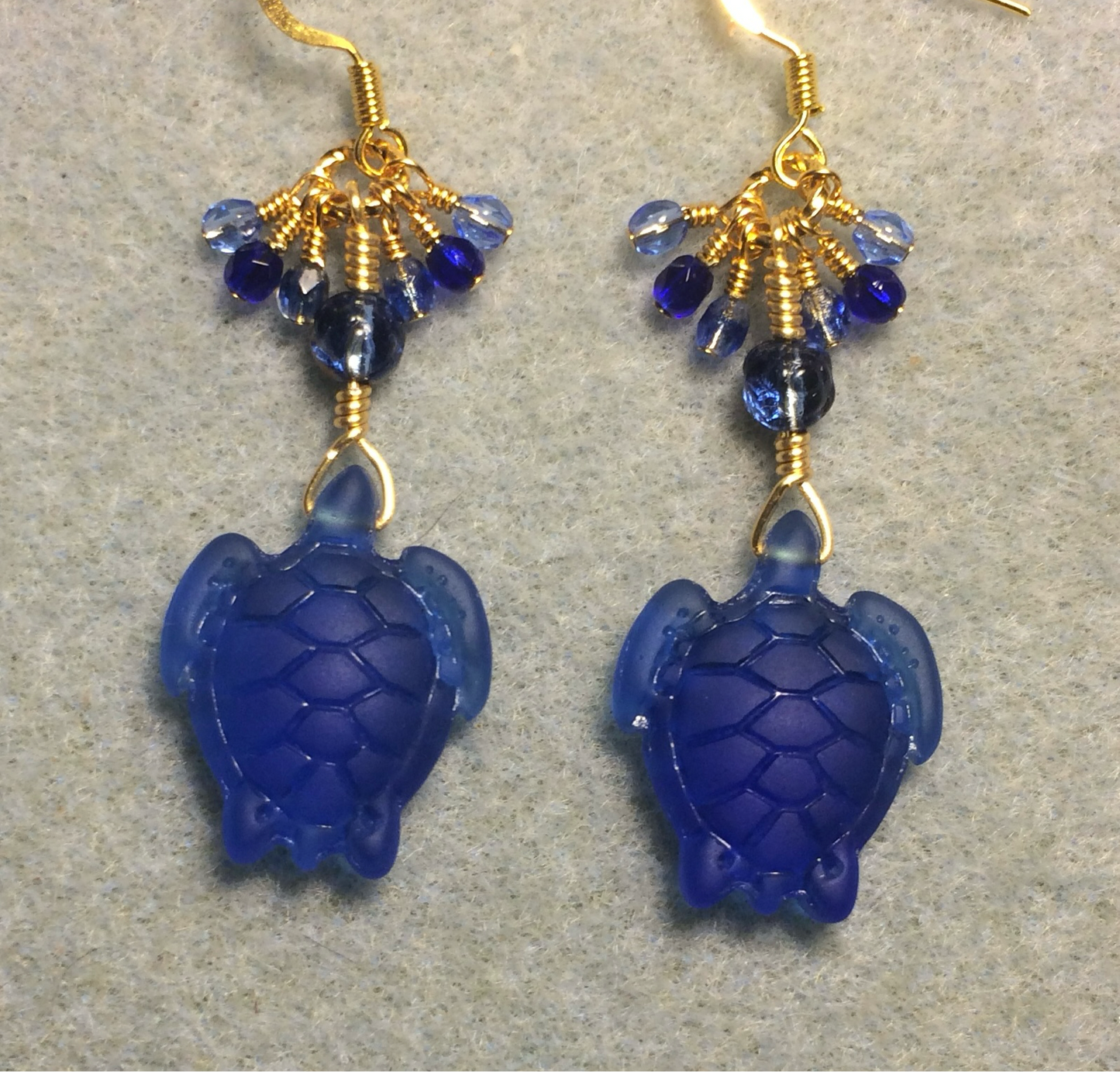 Dark blue sea glass sea turtle bead earrings adorned with dark blue Czech glass beads and small dangling dark blue and light blue Czech glass beads.