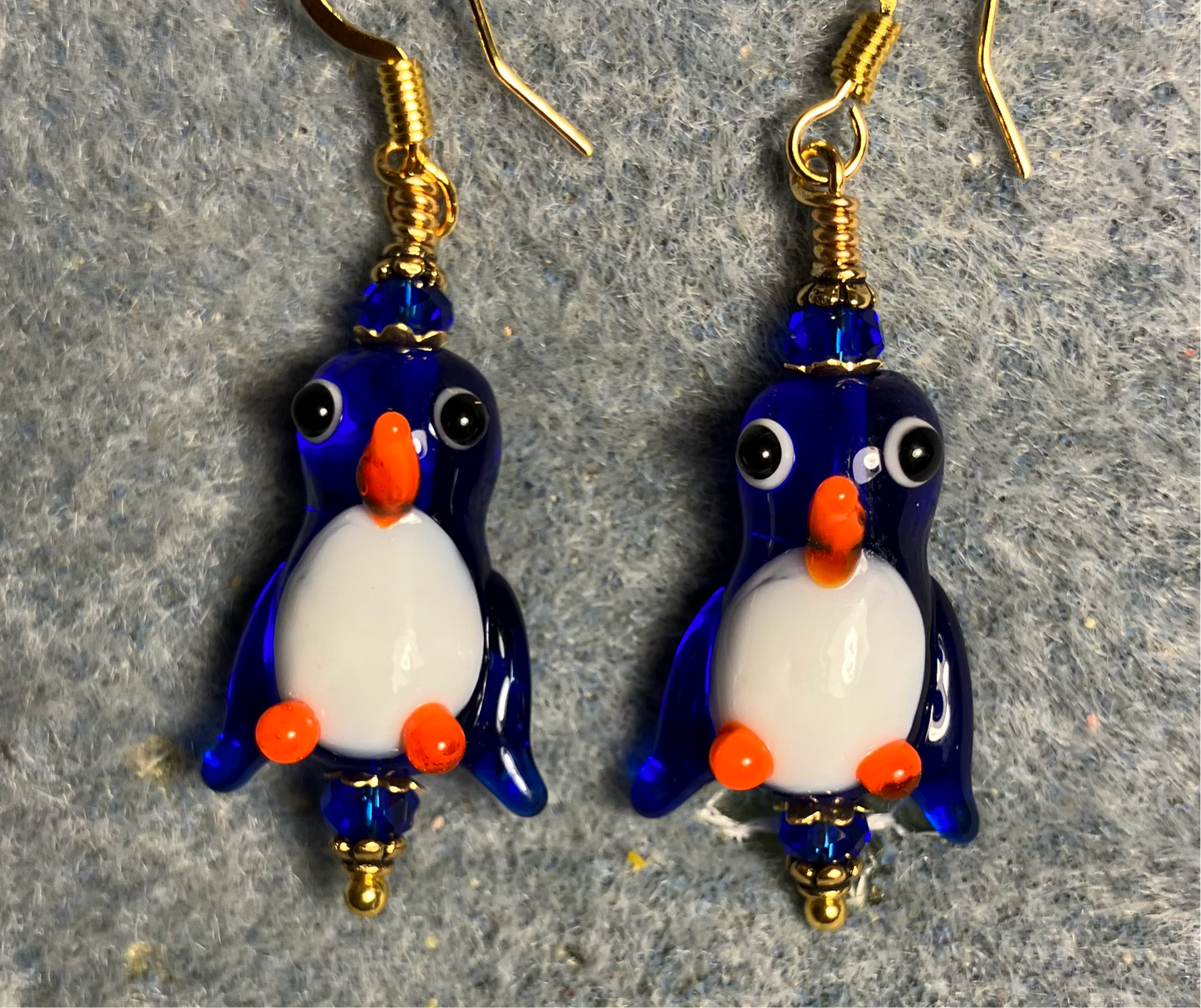 Translucent dark blue and white lamp work penguin bead earrings adorned with dark blue Chinese crystal beads.