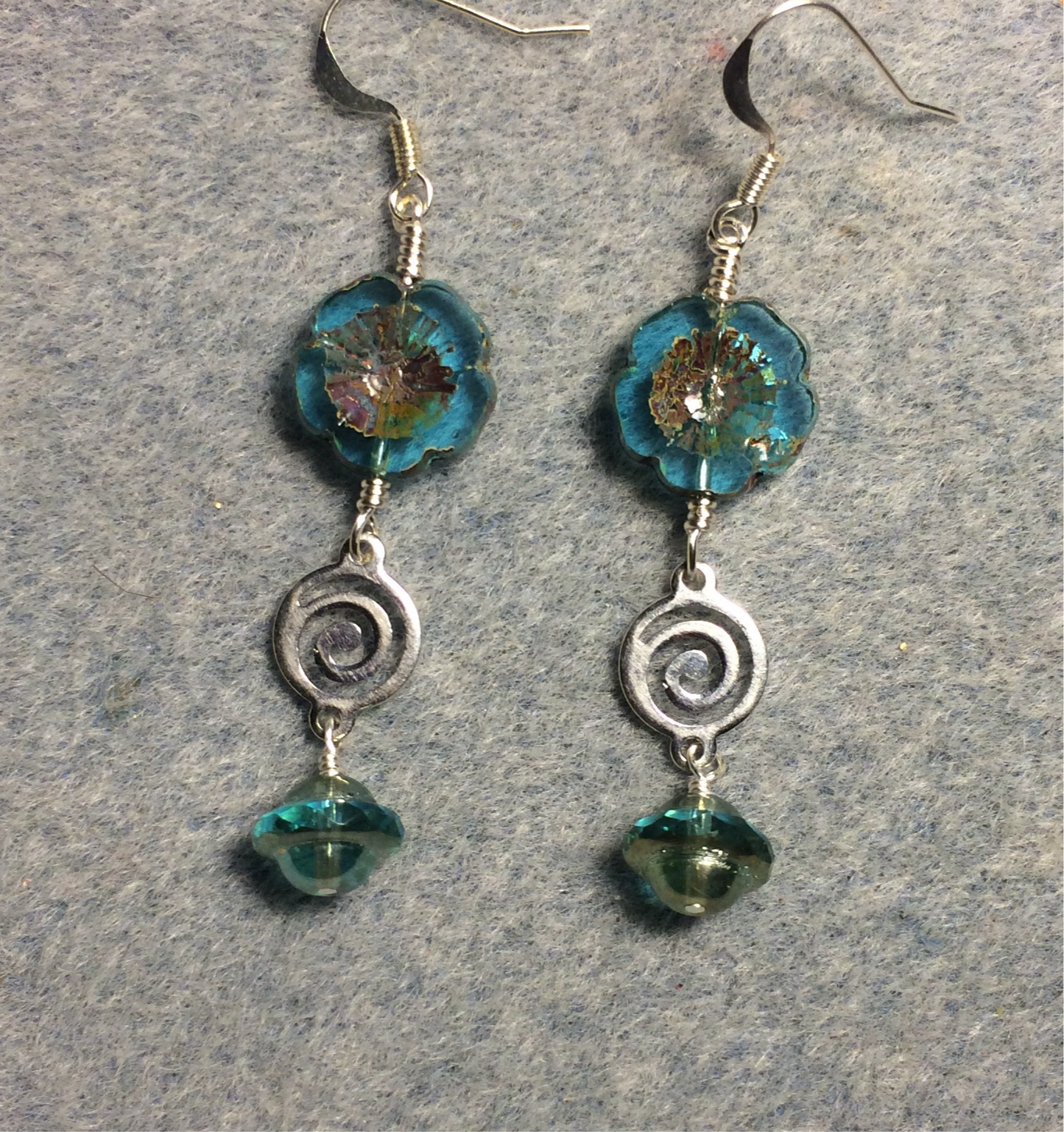 Translucent turquoise Czech glass pansy bead earrings adorned with silver swirly connectors and turquoise Czech glass Saturn beads.