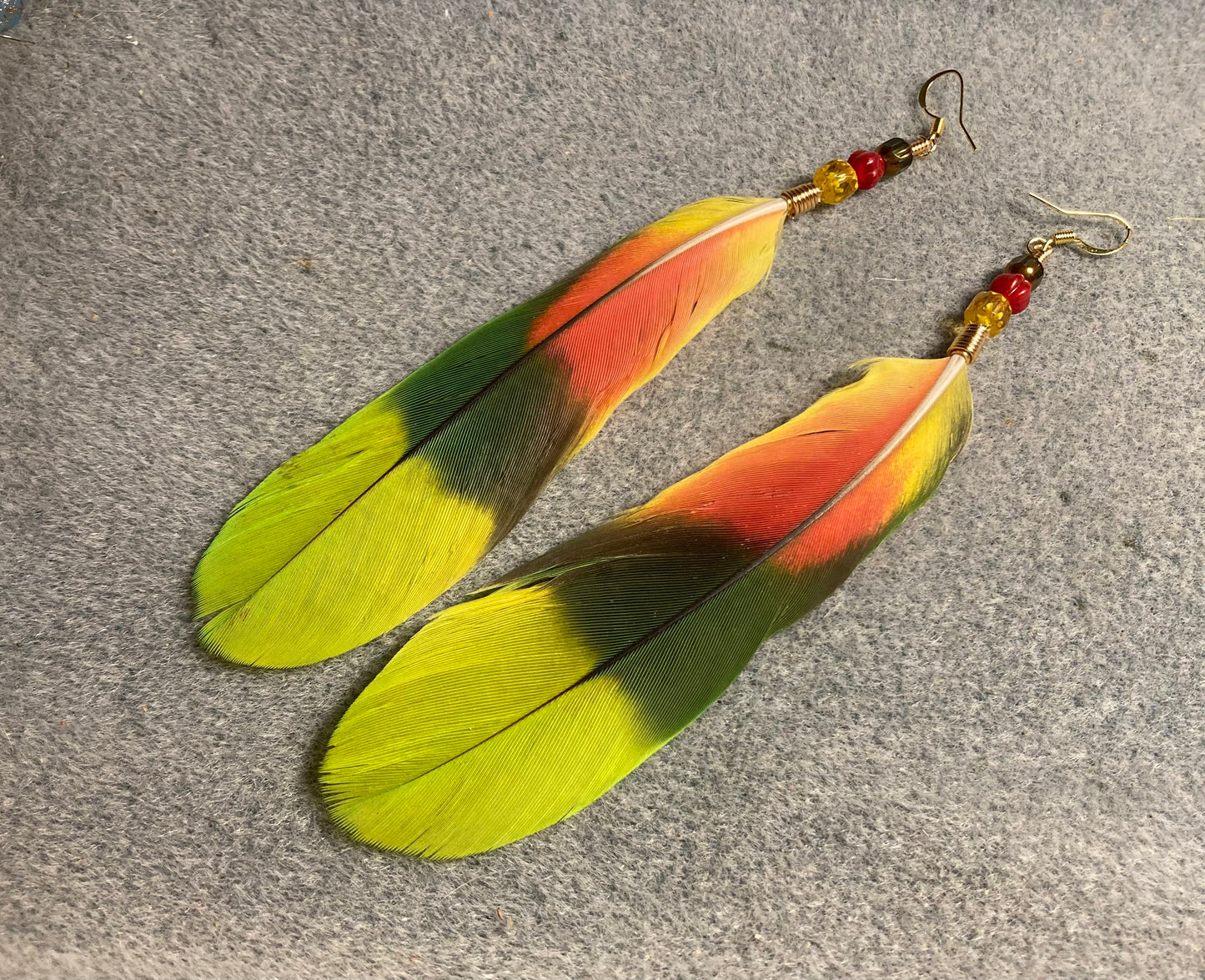 Double yellow headed Amazon parrot feather earrings adorned with yellow, red, and green Czech glass beads.