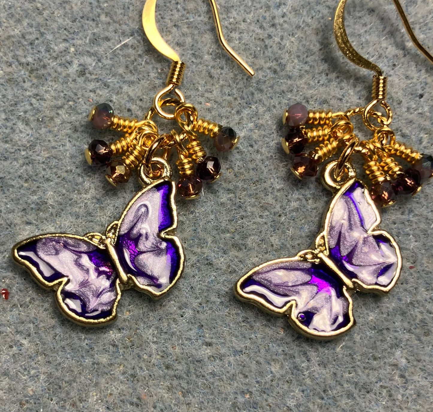 Purple and violet enamel butterfly charm earrings adorned with tiny dangling purple and violet Chinese crystal beads.