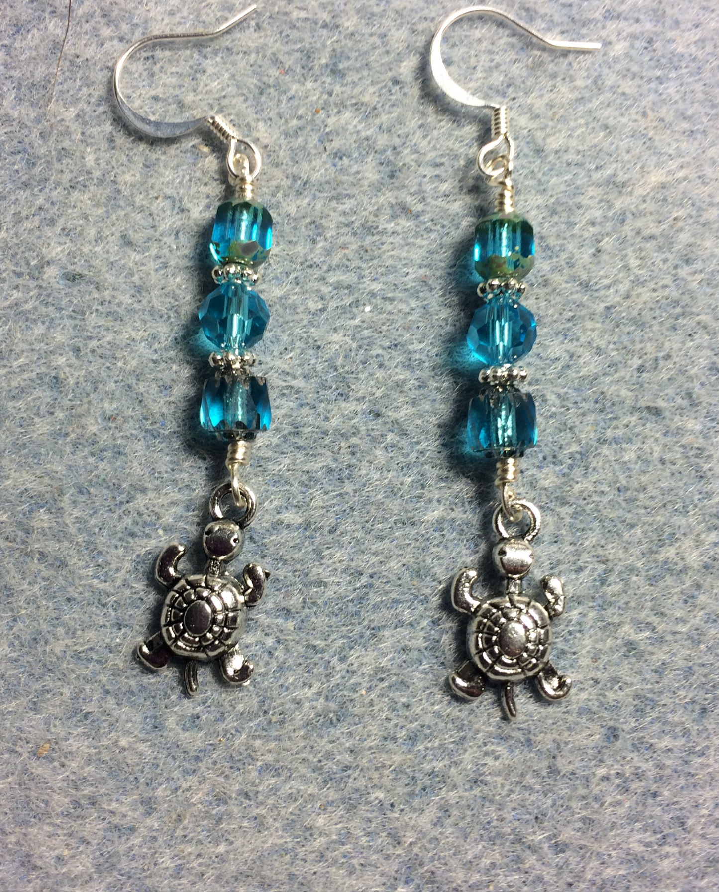 Small silver turtle charm earrings adorned with turquoise Czech glass beads