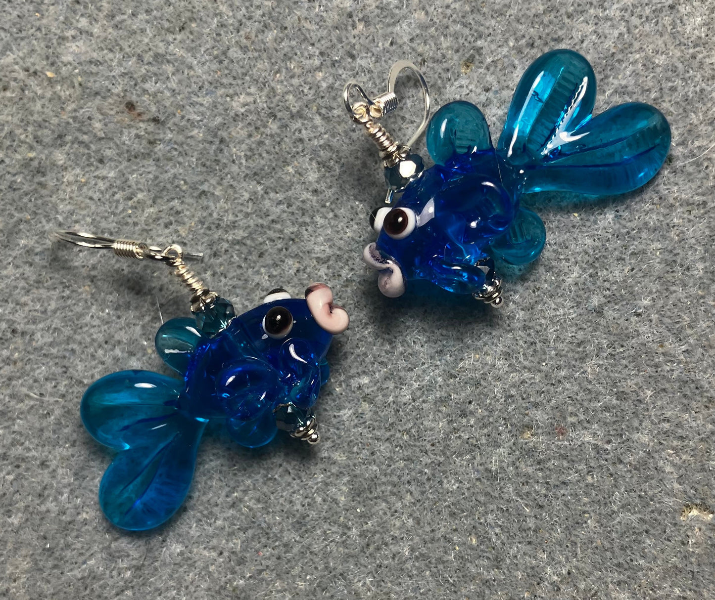 Translucent turquoise blue lamp work fish bead earrings adorned with turquoise blue Chinese crystal beads.