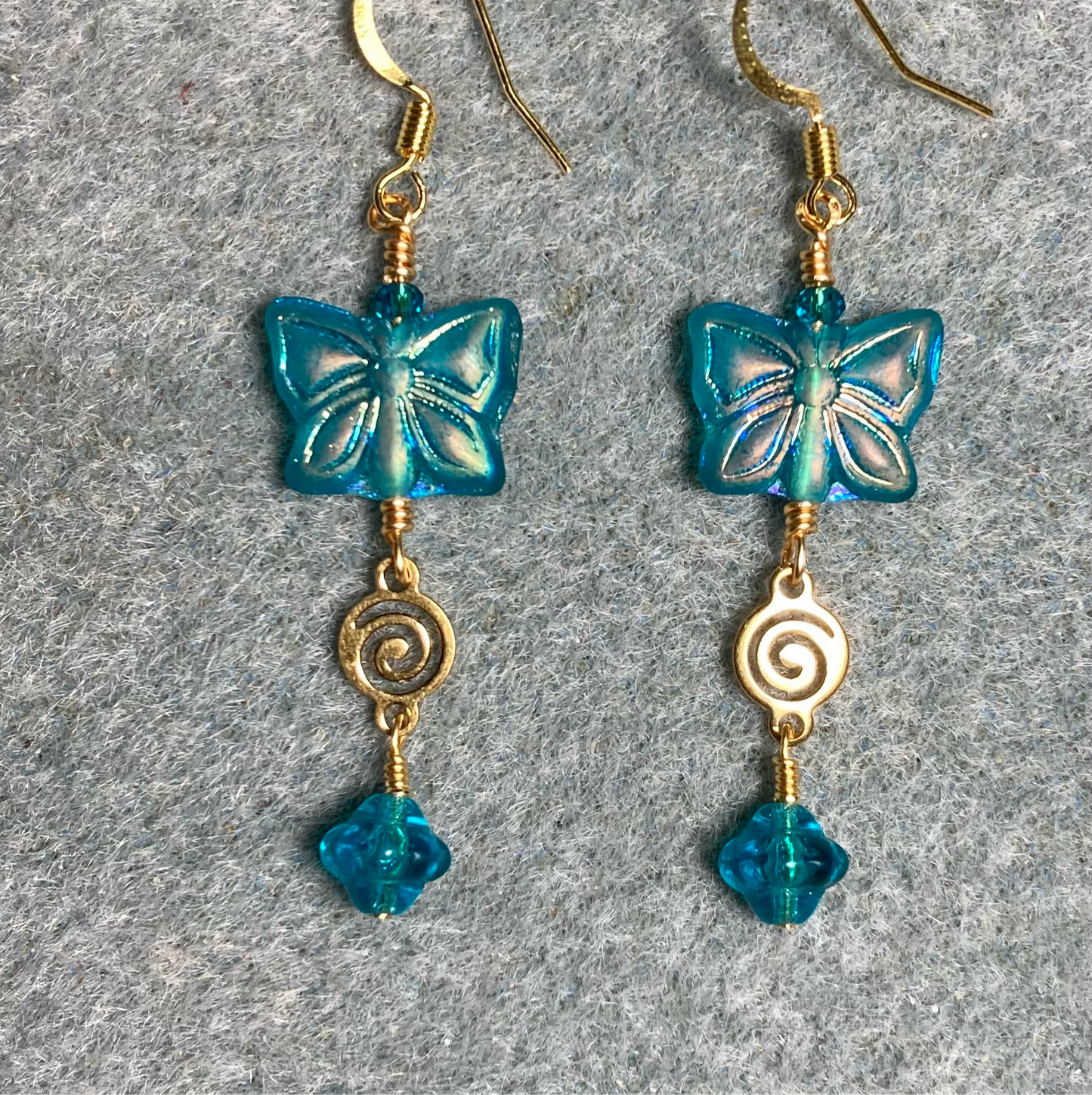 Sparkly turquoise Czech glass butterfly bead earrings adorned with gold swirly connectors and turquoise Czech glass Saturn beads.