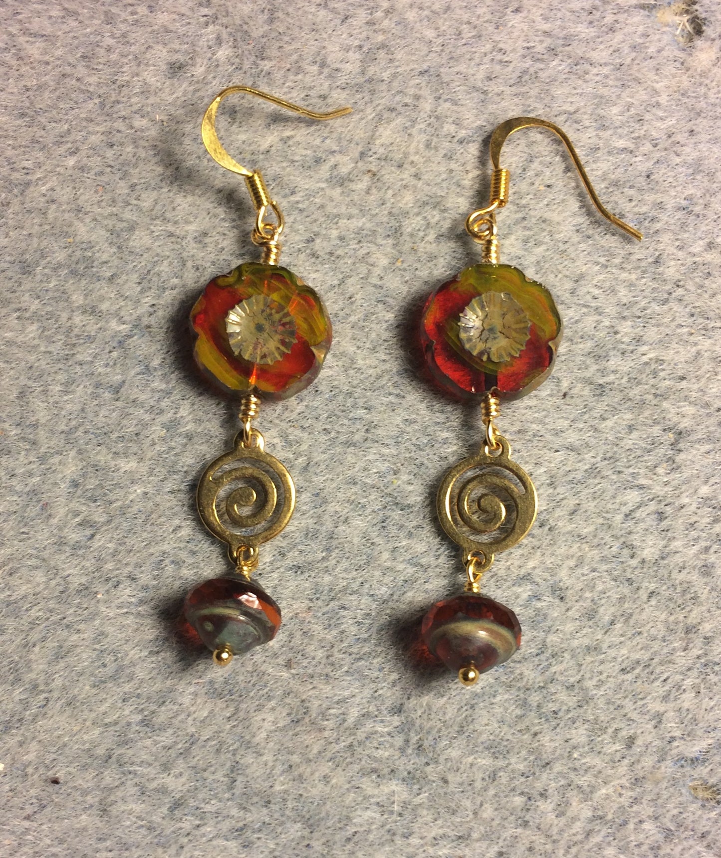 Red and yellow Czech glass pansy bead earrings adorned with gold swirly connectors and orange red Czech glass Saturn beads.