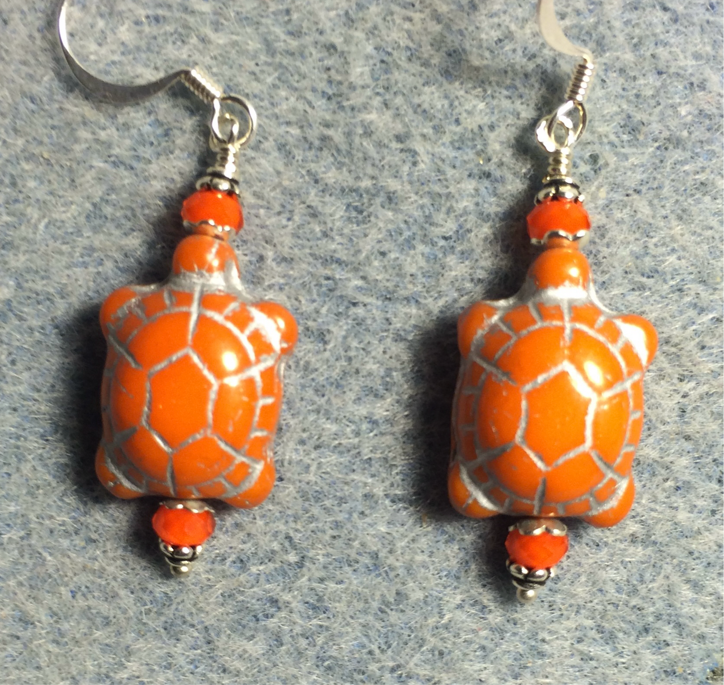 Opaque orange (with silver inlay) Czech glass turtle bead earrings adorned with orange Chinese crystal beads.