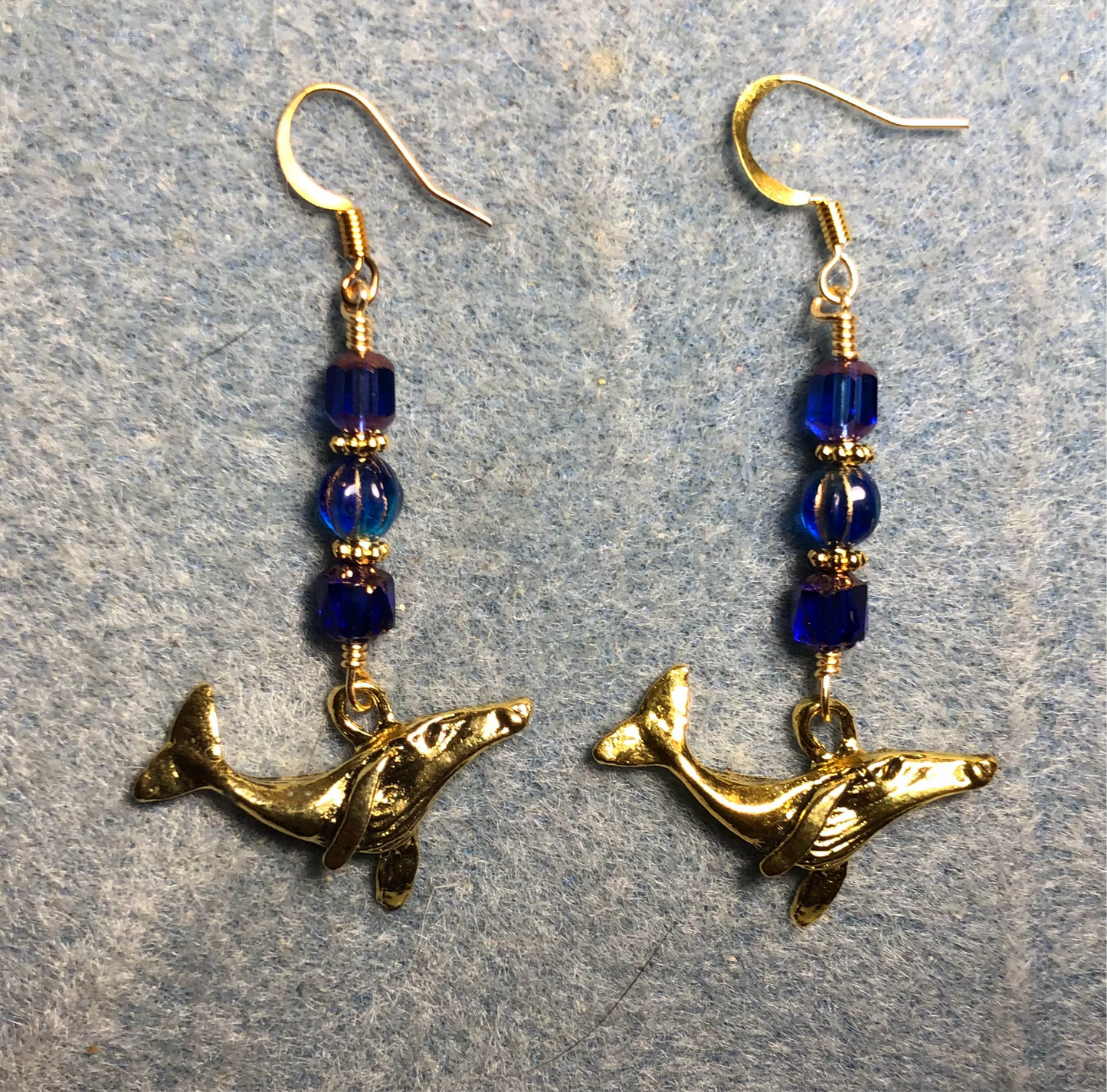 Gold humpback whale charm earrings adorned with dark blue Czech glass beads