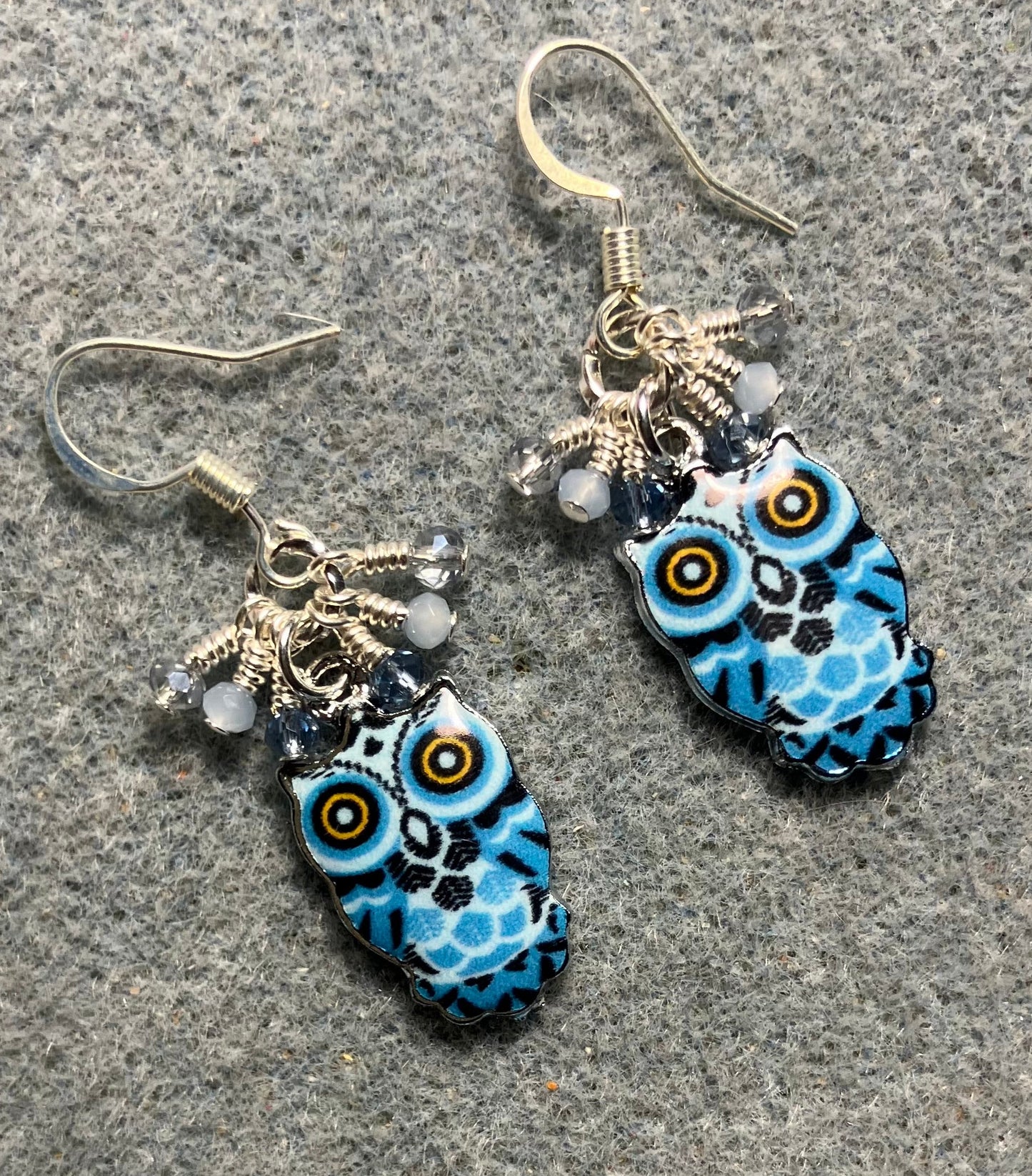 Blue, black, and silver enamel owl charm earrings adorned with tiny dangling dark blue and light blue Chinese crystal beads.