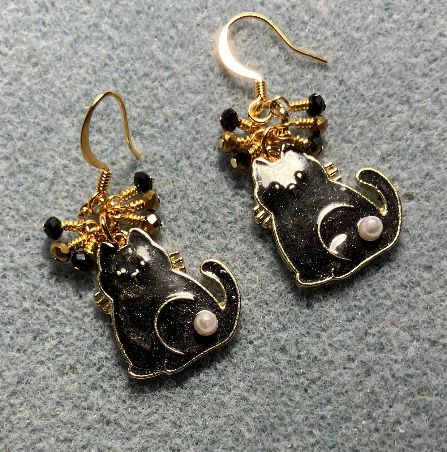 Black and gold enamel and pearl cat charm earrings adorned with tiny dangling black and gold Chinese crystal beads.