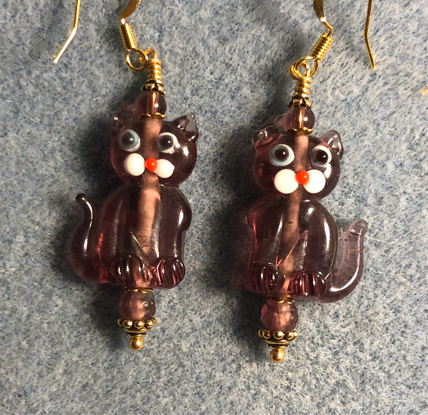 Translucent violet lamp work cat bead earrings adorned with violet Czech glass beads.
