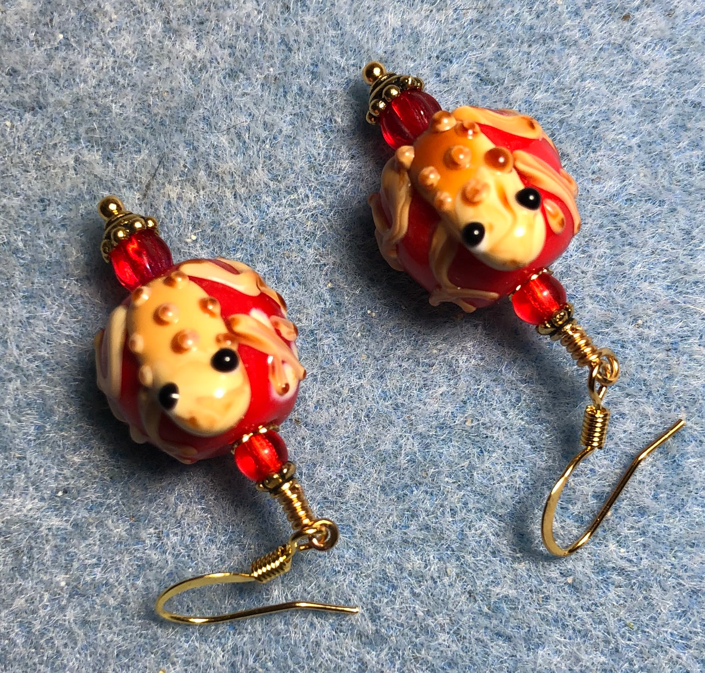 Red and tan lamp work frog bead earrings adorned with red Czech glass beads.