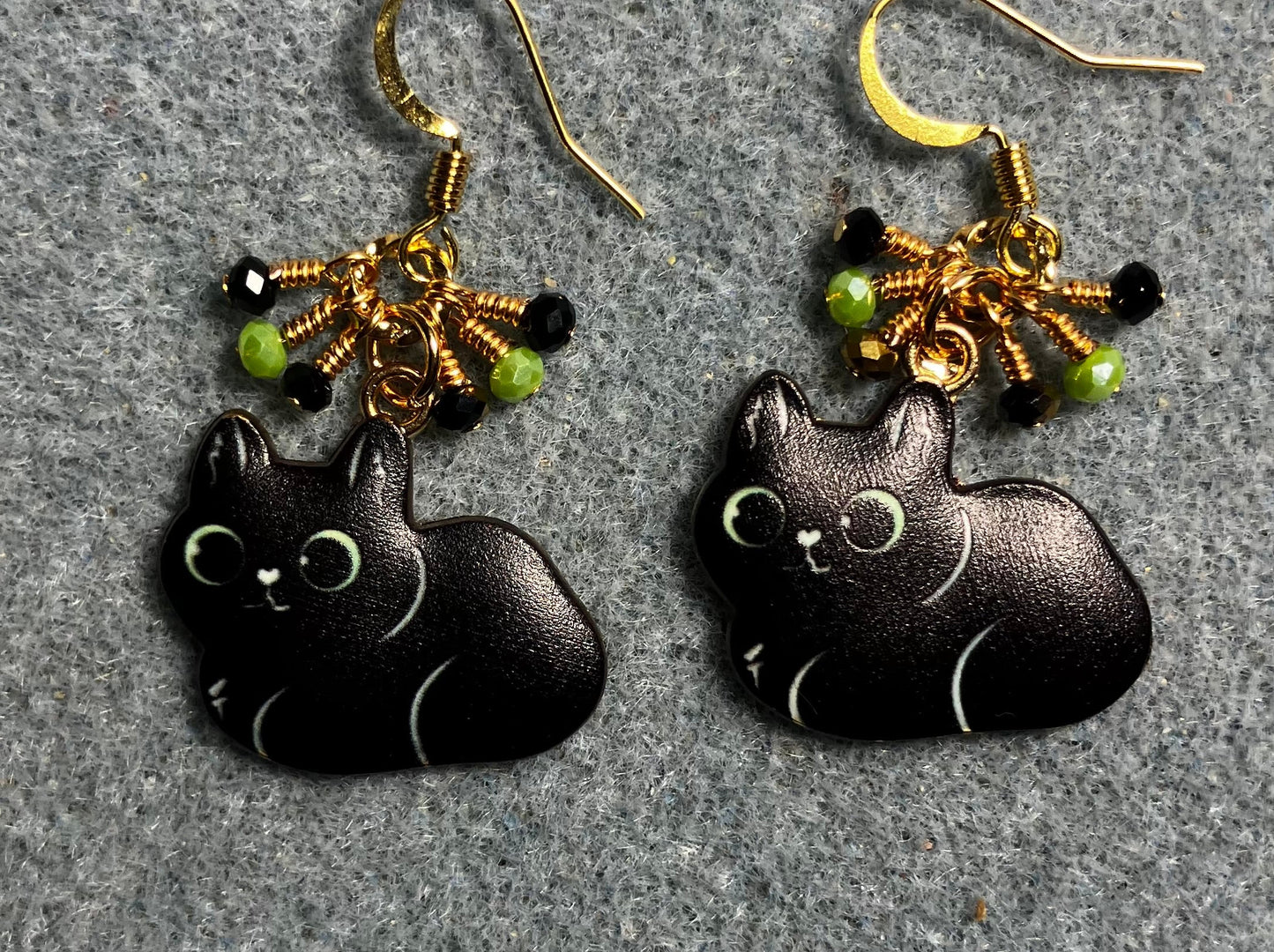 Black enamel cat charm earrings adorned with tiny dangling black, gold, and green Chinese crystal beads.