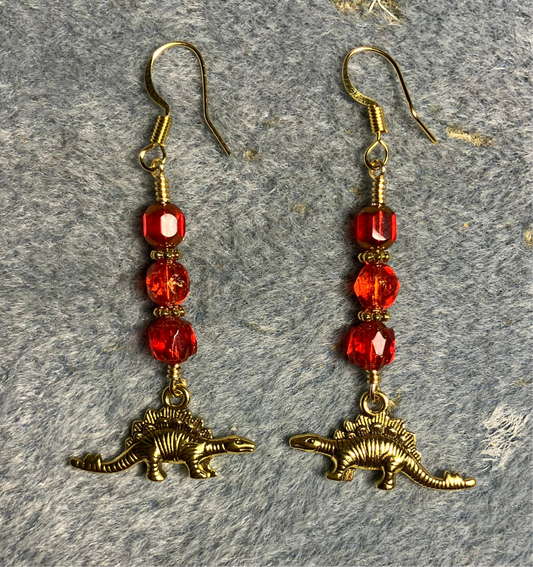 Gold stegosaurus charm earrings adorned with red Czech glass beads