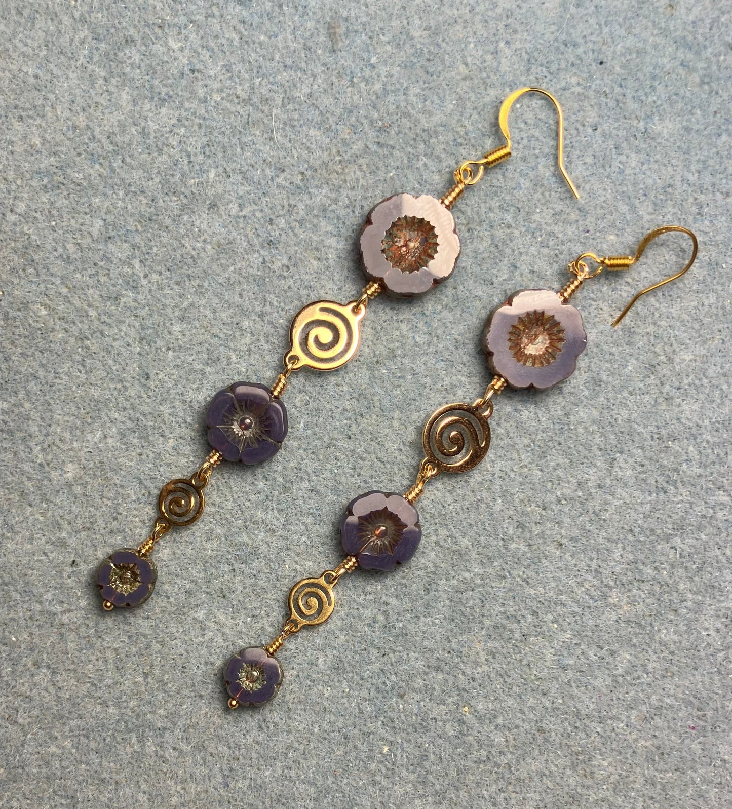 Extra long purple flower bead earrings made with three sizes of purple Czech glass pansy beads joined by gold swirly connectors.