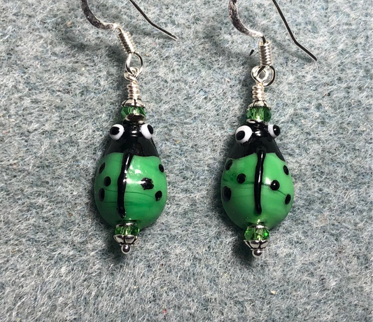 Small green and black lamp work ladybug bead earrings adorned with green Chinese crystal beads.