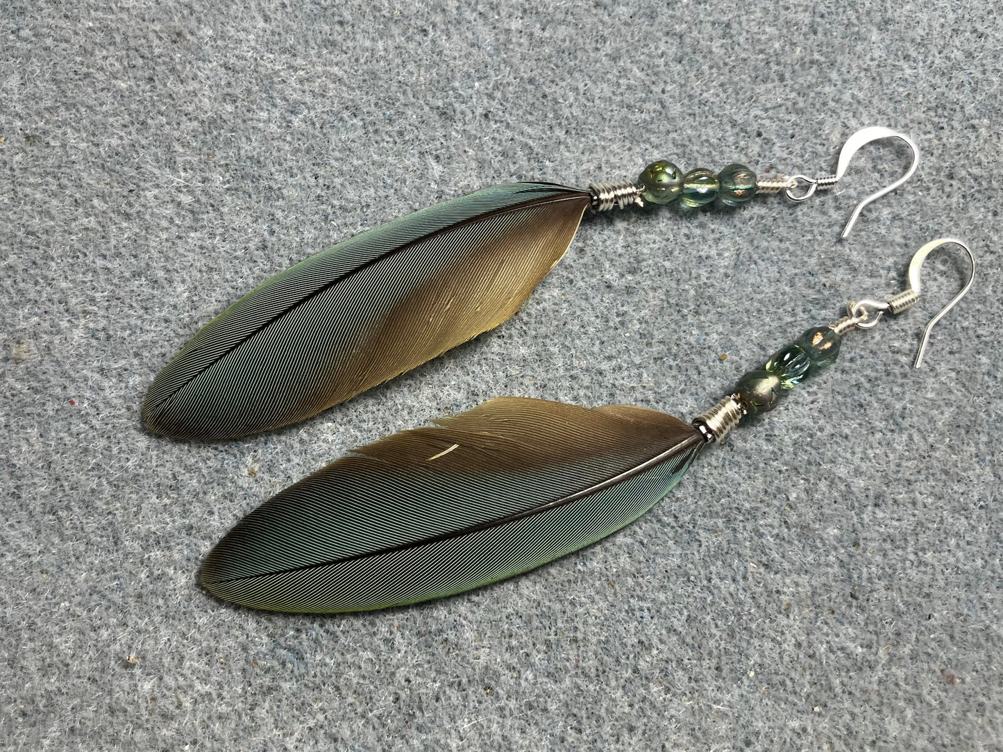 Small pointed green gray red-fronted macaw feather earrings adorned with small green gray Czech glass beads.