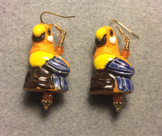 Large orange, yellow, and blue ceramic parrot bead earrings adorned with orange Czech glass beads.