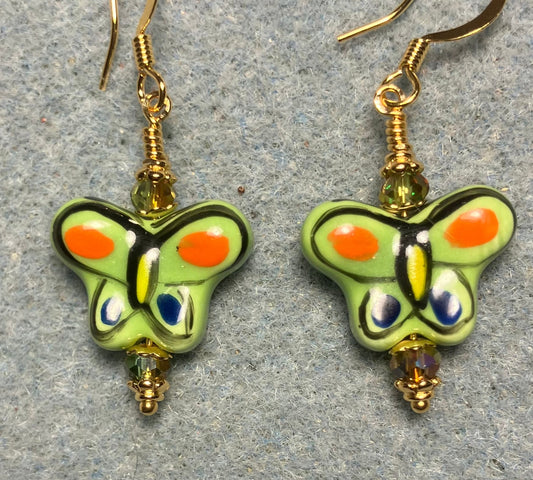 Olive green and orange ceramic butterfly bead earrings adorned with sparkly olive green Chinese crystal beads.