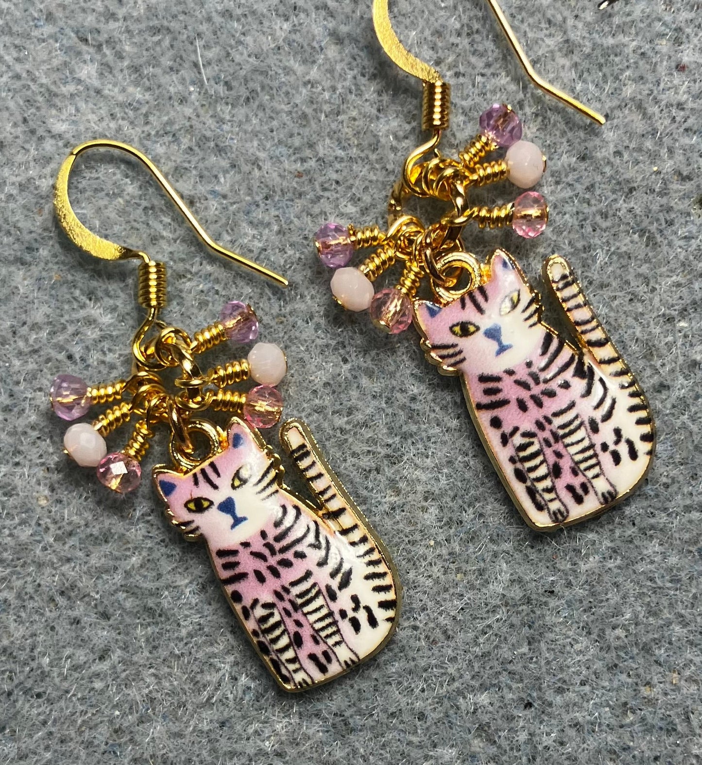 Light pink, black, and white enamel striped cat charm earrings adorned with tiny dangling light pink Chinese crystal beads.
