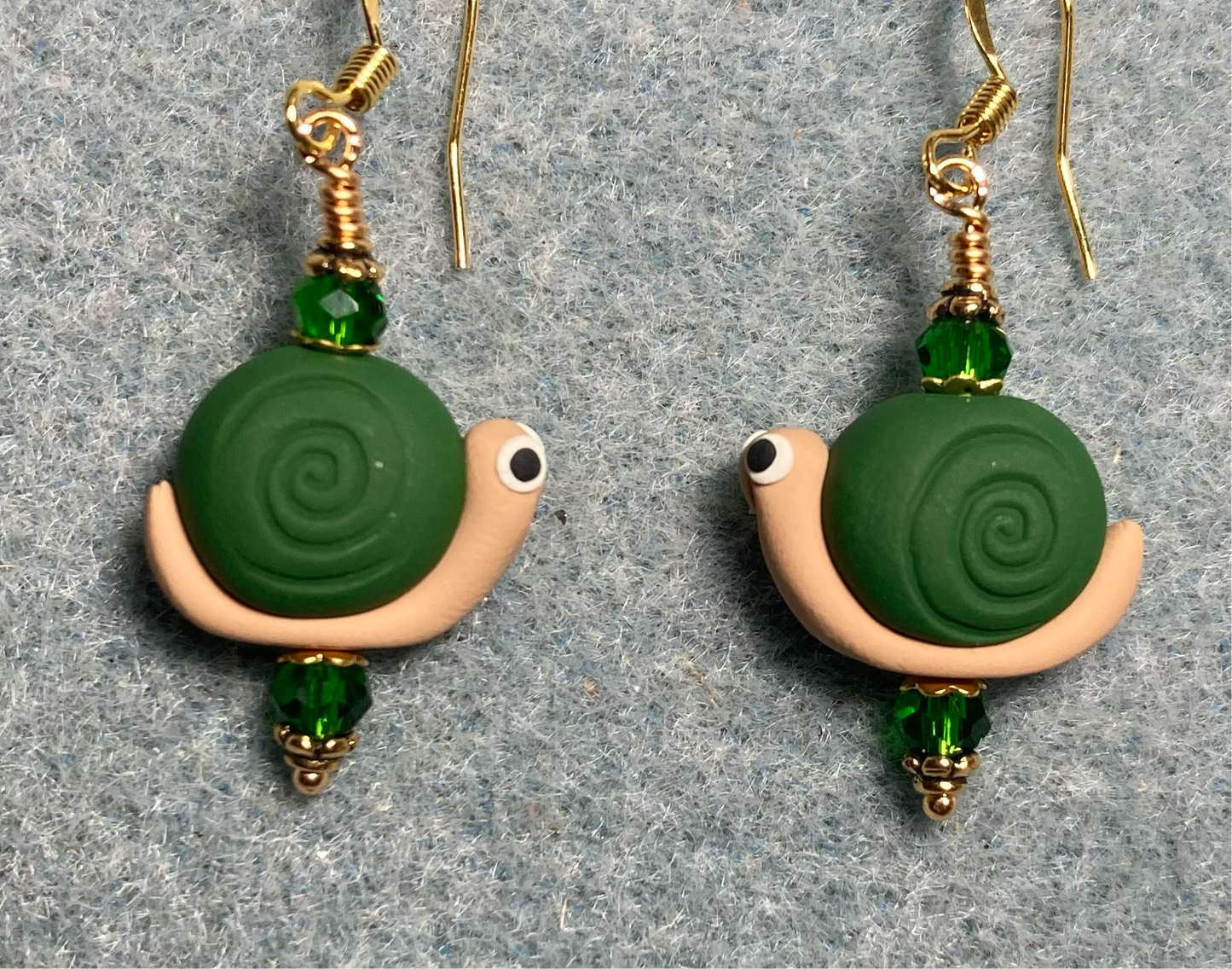 Dark green and tan polymer clay snail bead earrings adorned with dark green Chinese crystal beads.