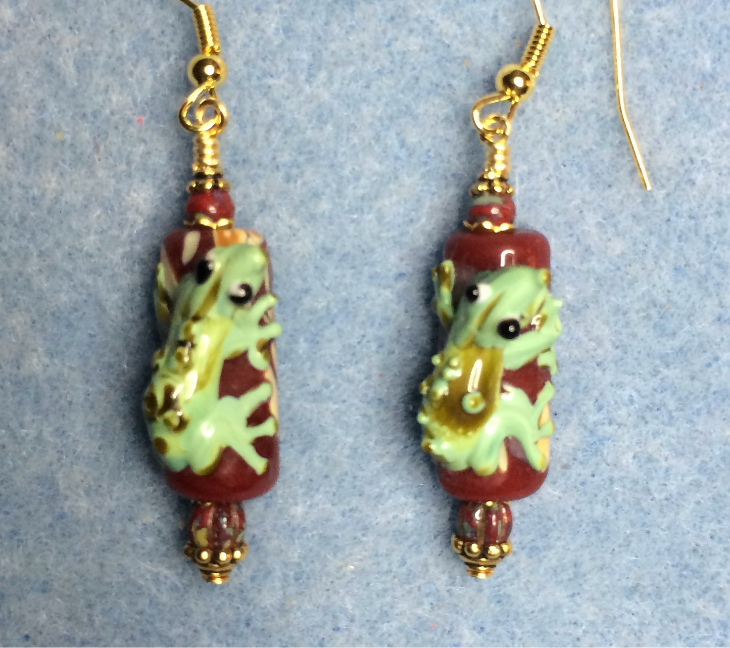 Dark red and green lamp work lizard bead earrings adorned with red Picasso Czech glass beads.
