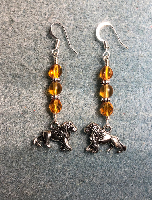 Silver lion charm earrings adorned with amber Czech glass beads.