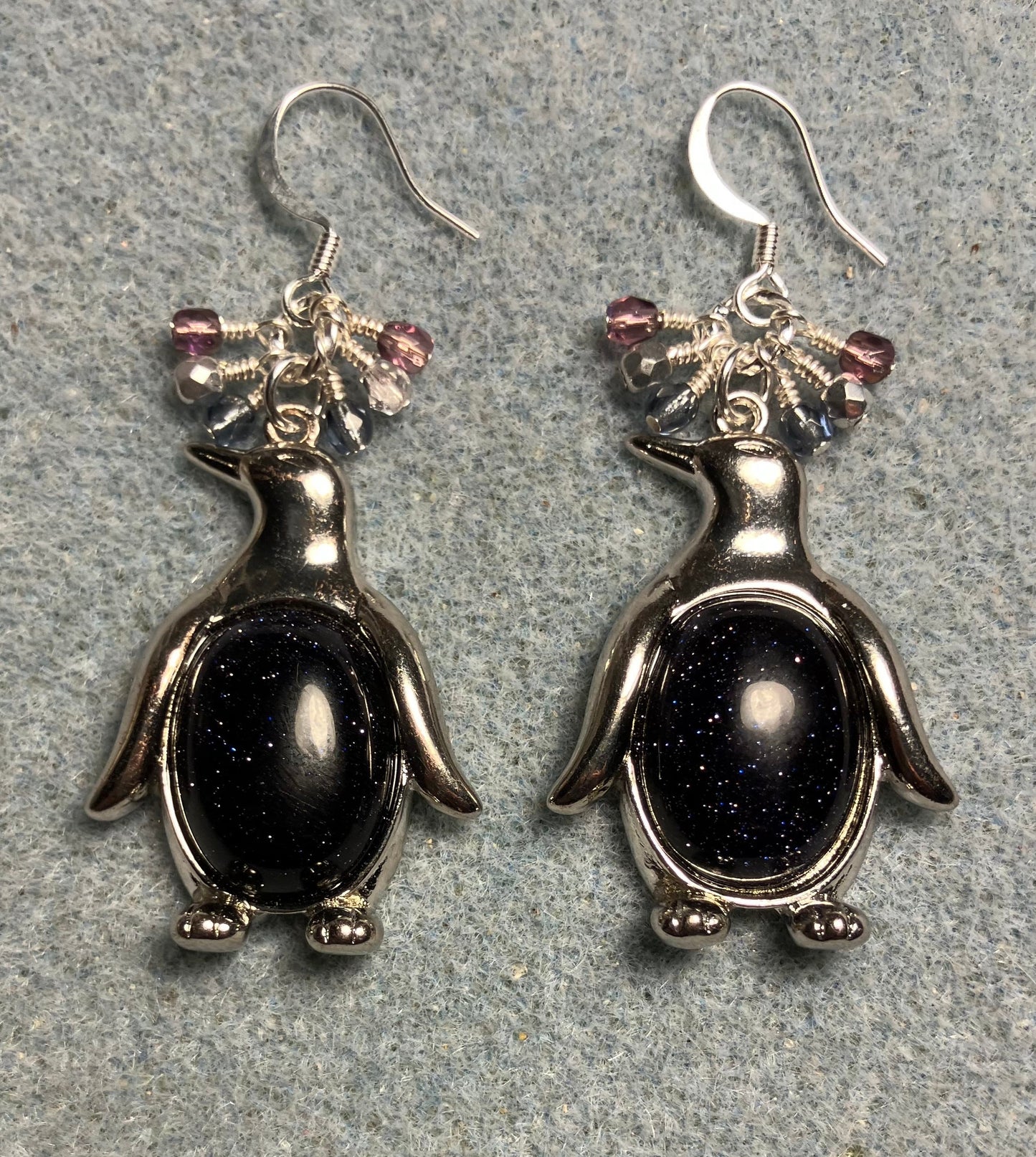 Large silver and blue goldstone gemstone penguin charm earrings adorned with small dangling blue, purple, and silver Czech glass beads.