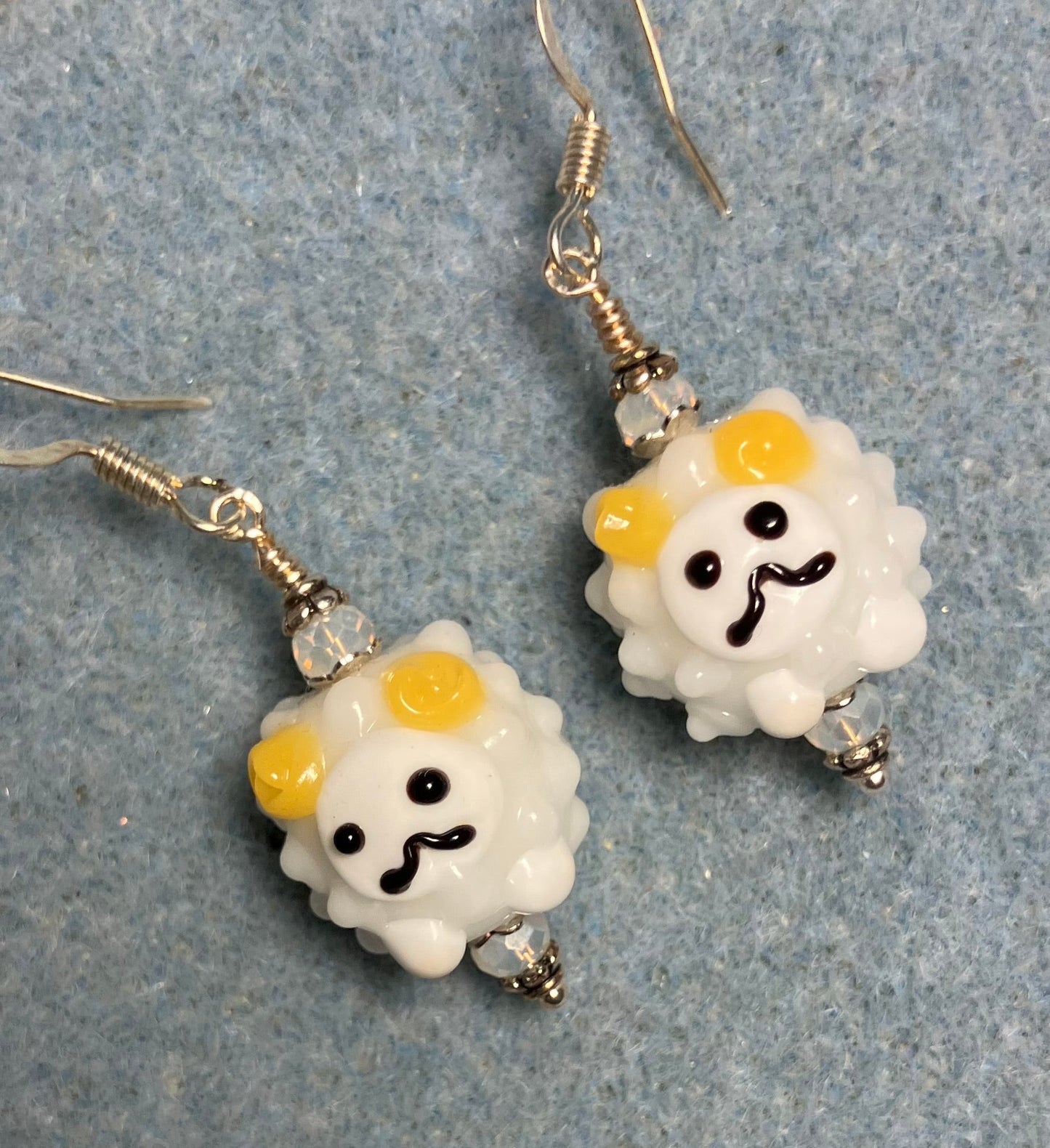 White, yellow, and black lamp work sheep bead earrings adorned with white Chinese crystal beads.