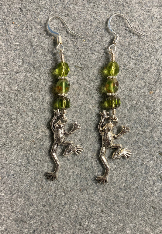 Long silver jumping frog charm earrings adorned with olive green Czech glass beads.