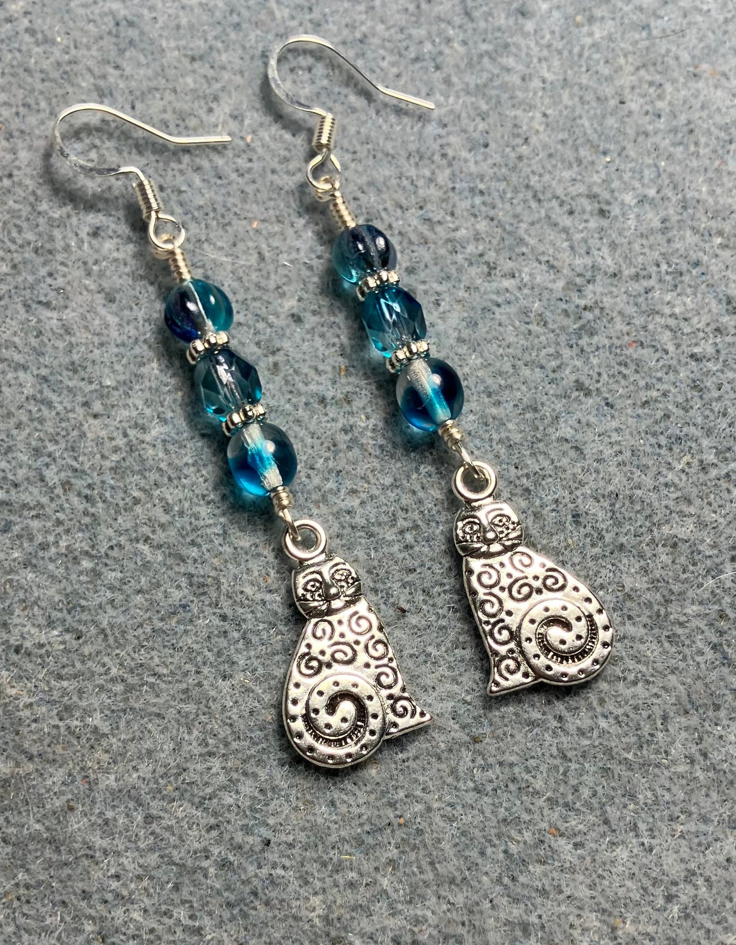 Silver swirly tailed cat charm earrings adorned with turquoise Czech glass beads