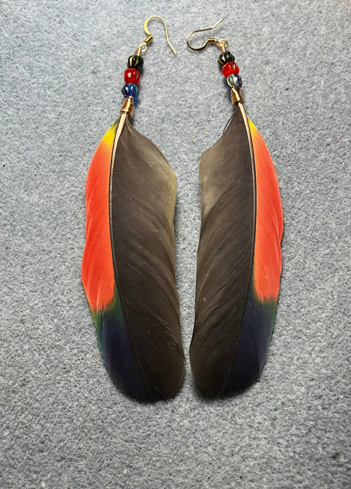 Black, dark blue, red, and green Amazon wing feather earrings adorned with blue, red, and green Czech glass beads.