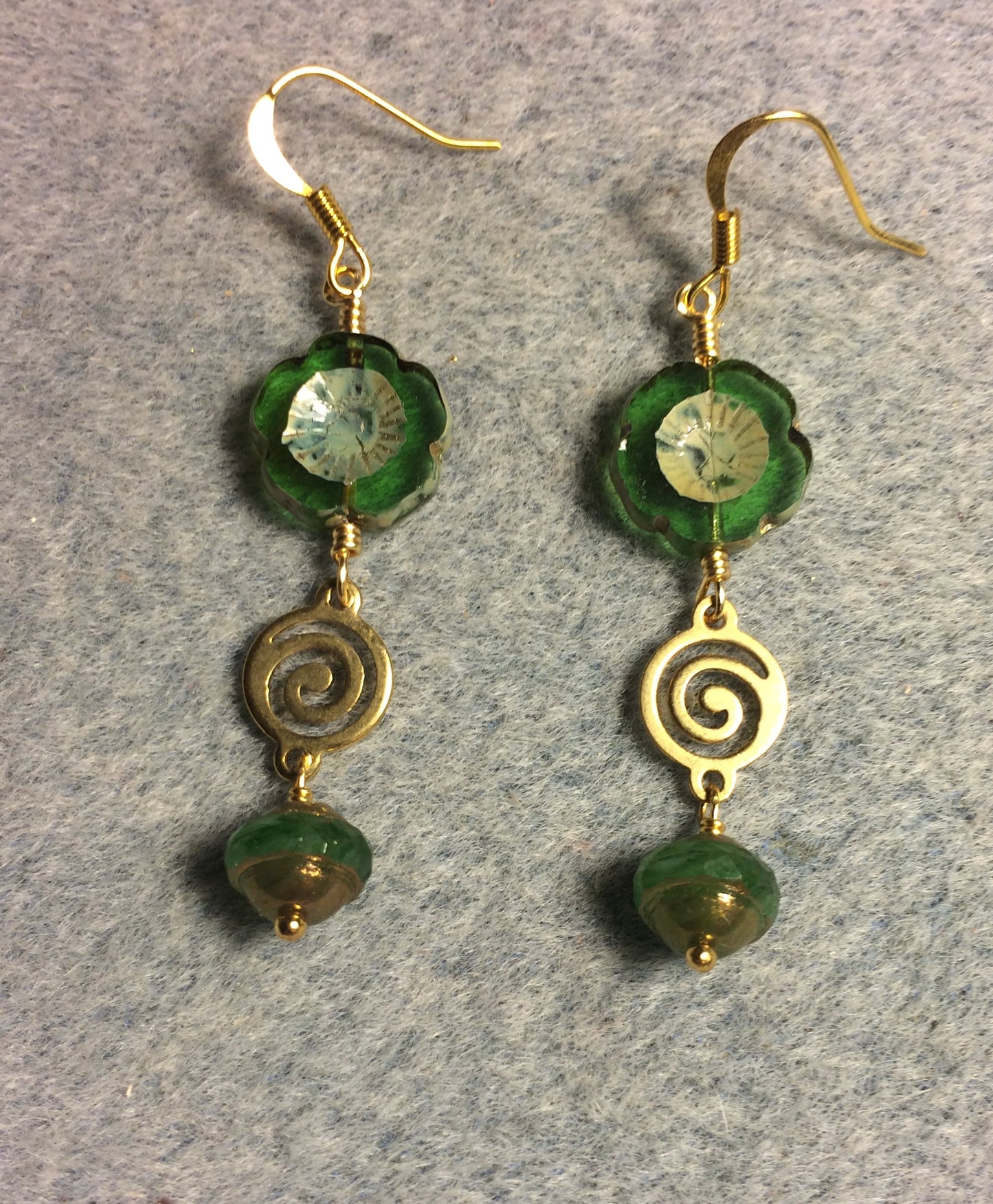 Emerald green Czech glass pansy bead earrings adorned with gold swirly connectors and emerald green and gold Czech glass Saturn beads.