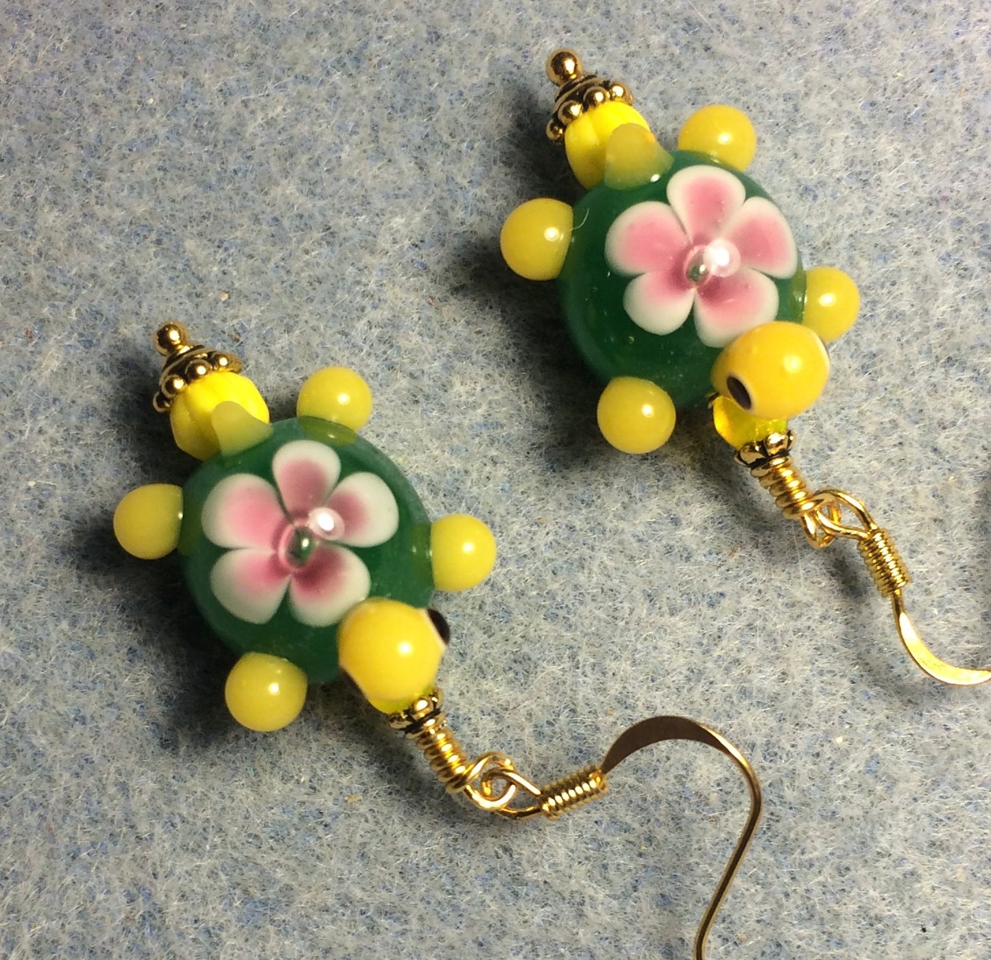 Green, yellow, and pink lamp work turtle bead earrings adorned with yellow Czech glass beads.