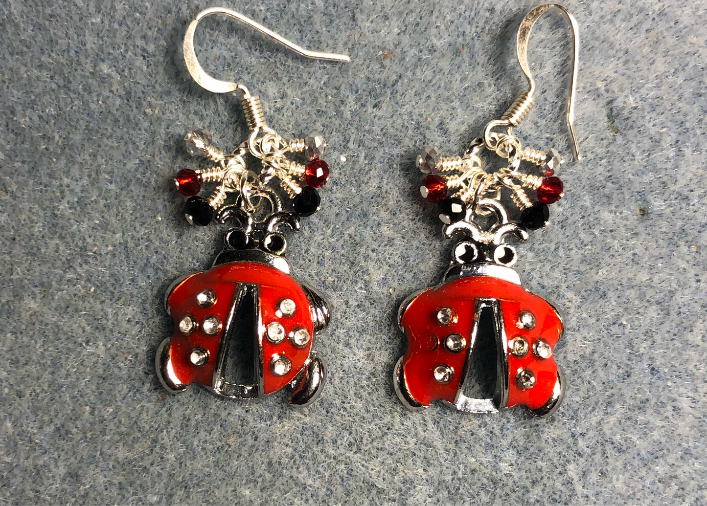 Small red, black, and silver enamel ladybug charm earrings adorned with tiny dangling red, black, and silver Chinese crystal beads.