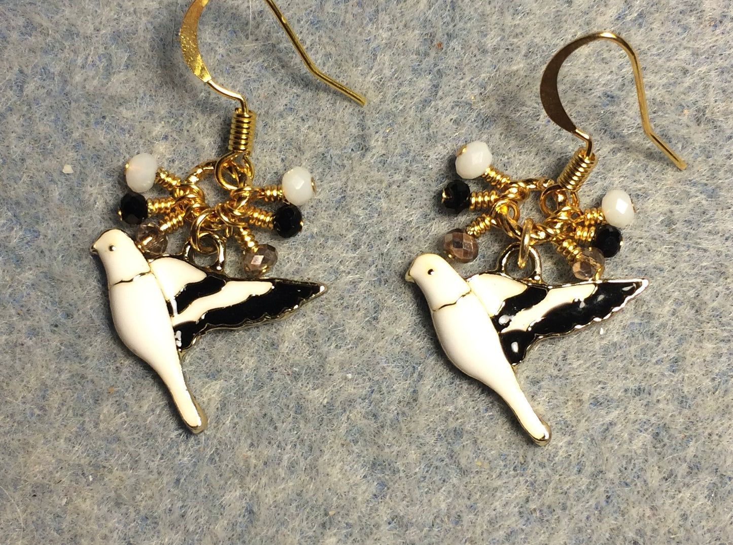 White, black, and gold enamel parakeet charm earrings adorned with tiny dangling white, black, and gold Chinese crystal beads.