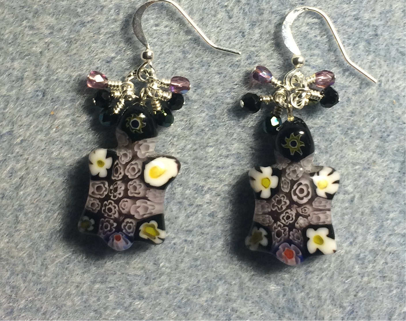 Purple millefiori lamp work turtle bead earrings adorned with tiny dangling purple, black, and green Czech glass beads.