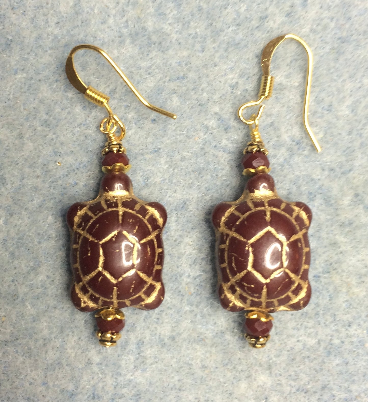 Dark reddish brown (with gold wash) Czech glass turtle bead earrings adorned with dark red Chinese crystal beads.