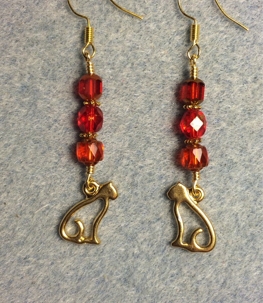Gold silhouette cat charm earrings adorned with red Czech glass beads