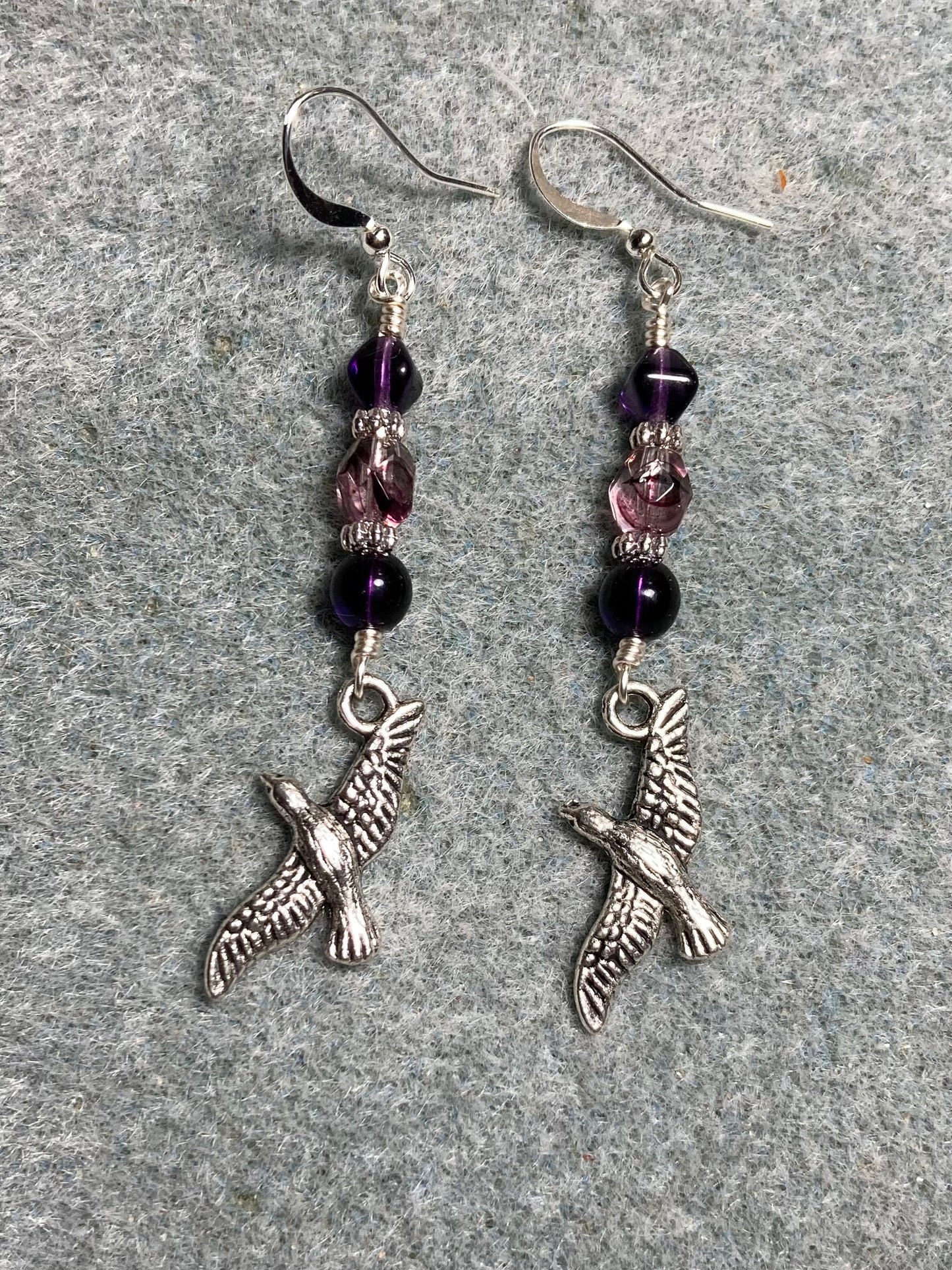 Silver flying bird charm earrings adorned with purple and violet Czech glass beads