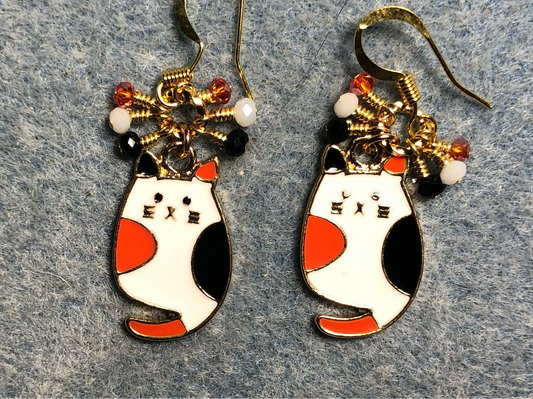 White, orange, and black enamel calico cat charm earrings adorned with tiny dangling white, orange, and black Chinese crystal beads.