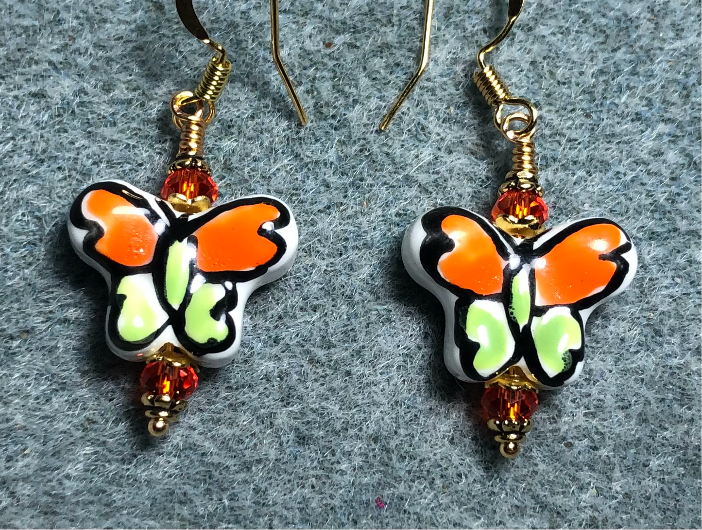 Orange and olive green ceramic butterfly bead earrings adorned with orange Chinese crystal beads.