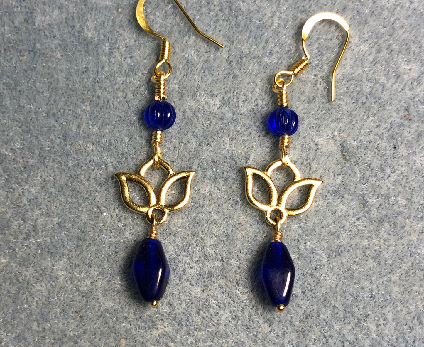 Small gold lotus flower connector charm earrings adorned with dark blue Czech glass drop beads and dark blue Czech glass melon beads.