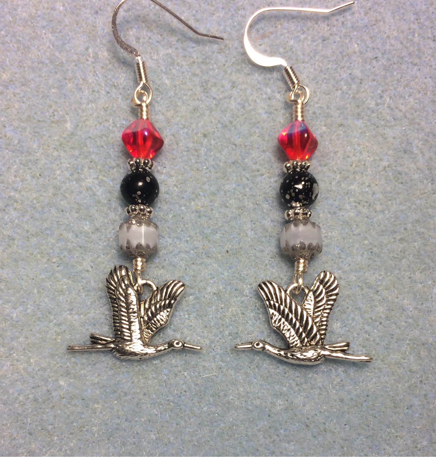 Silver flying crane charm earrings adorned with white, black, and red Czech glass beads.