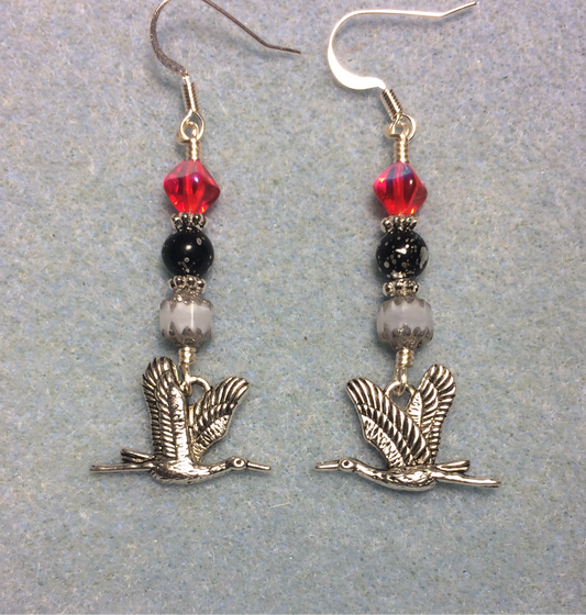 Silver flying crane charm earrings adorned with white, black, and red Czech glass beads.