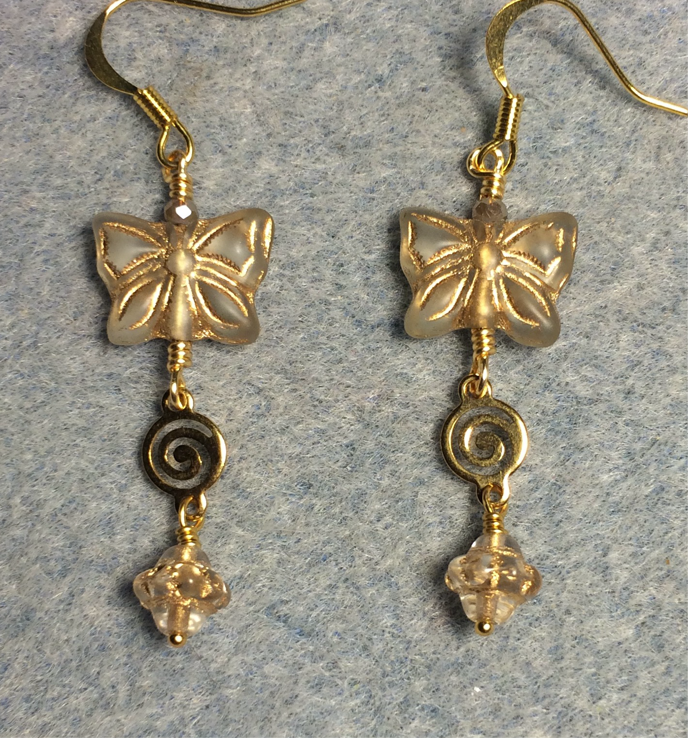 Tan Czech glass butterfly bead earrings adorned with gold swirly connectors and tan Czech glass Saturn beads.