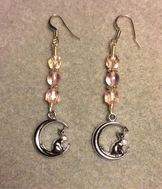 Silver cat sitting on a crescent moon charm earrings adorned with light pink Czech glass beads