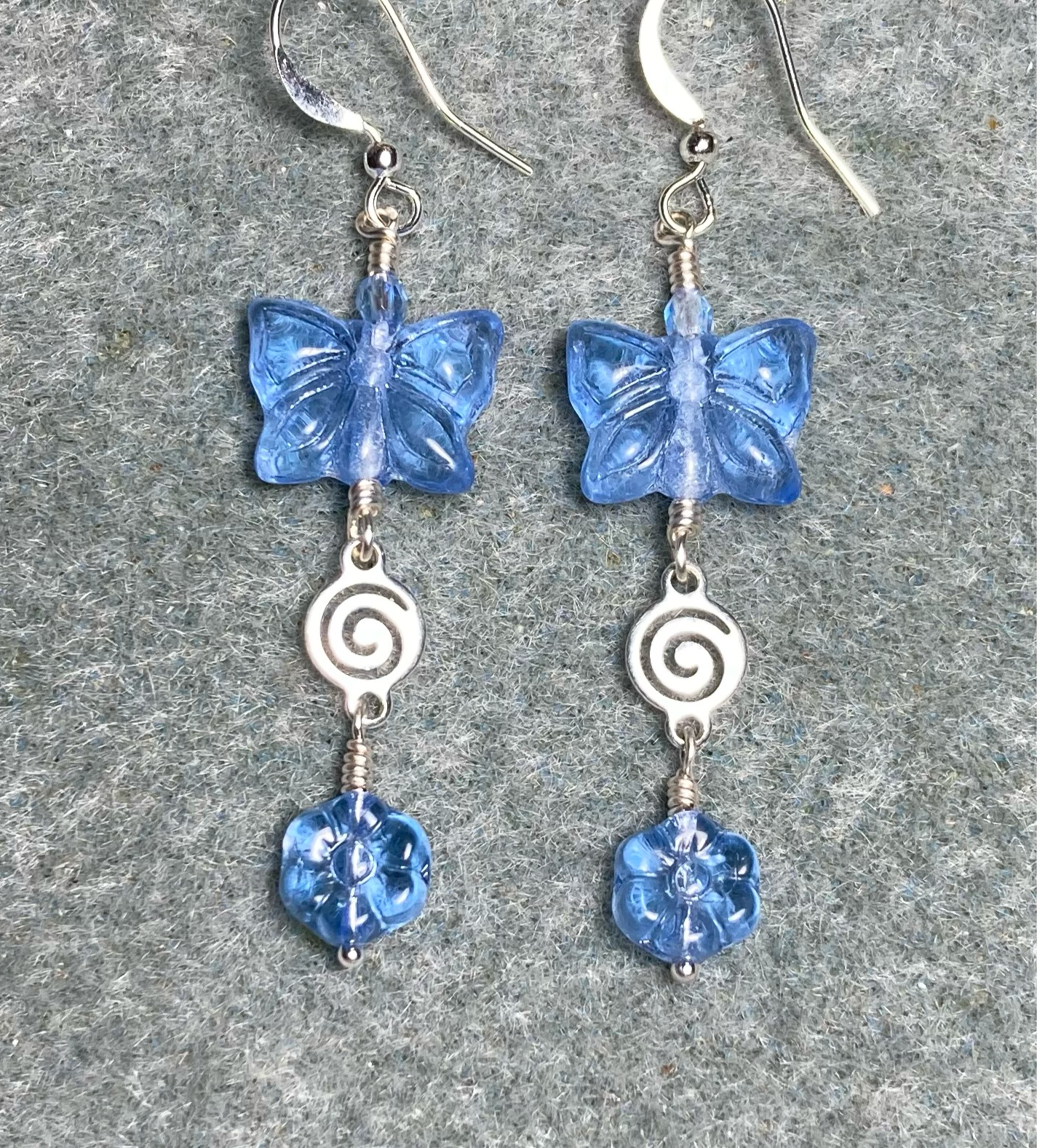 Light blue Czech glass butterfly bead earrings adorned with silver swirly connectors and light blue Czech glass daisy beads.