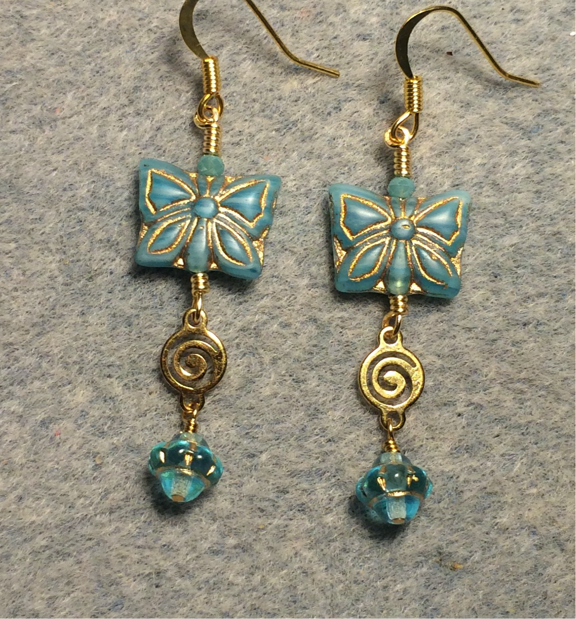 Aqua Czech glass butterfly bead earrings adorned with gold swirly connectors and aqua Czech glass Saturn beads.