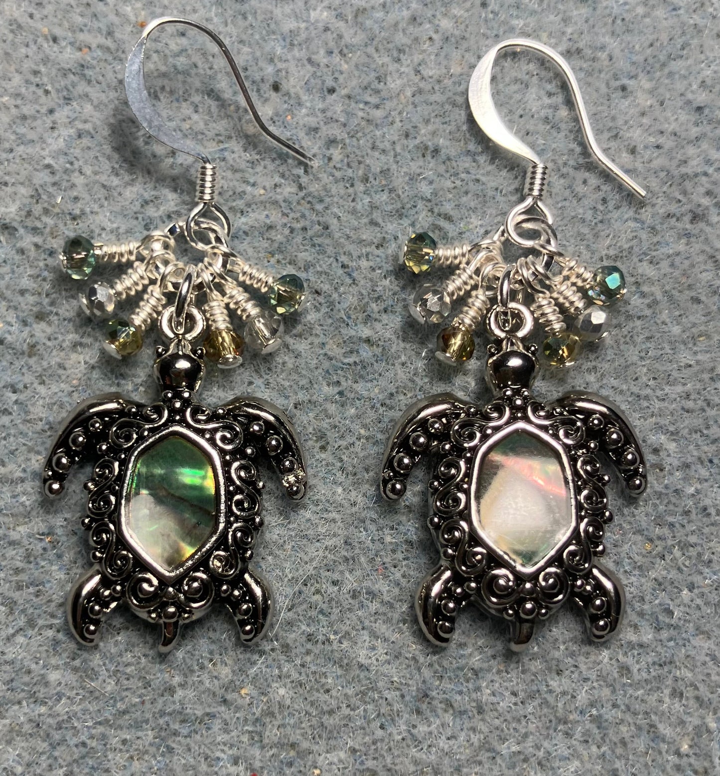 Ornate silver and abalone turtle charm earrings adorned with tiny dangling green and silver Chinese crystal beads.